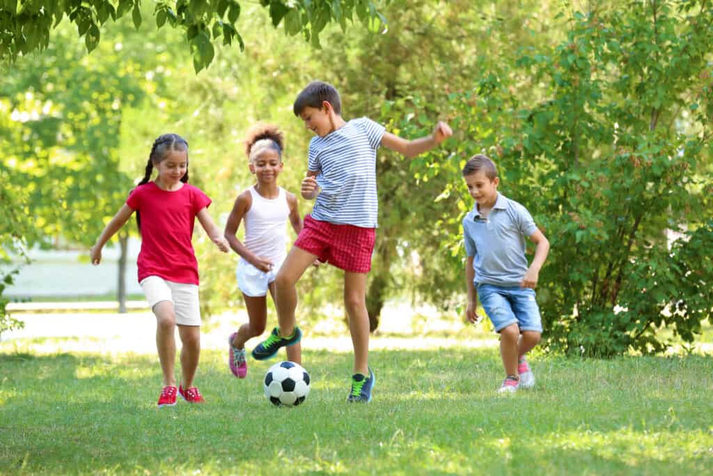 Crianças jogando futebol juntas em um parque